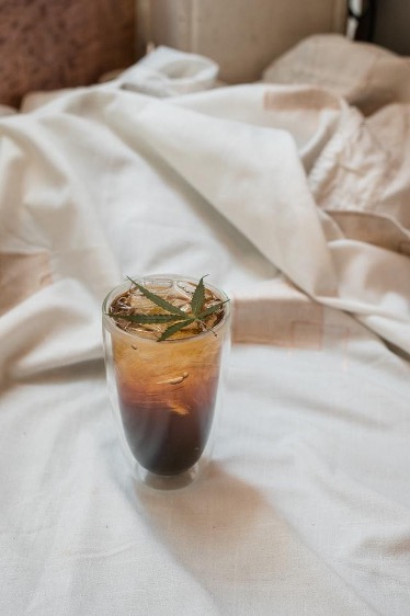 a cannabis beverage on a bed with a weed leaf on top