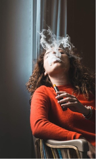Girl blowing vapour into the air from her vape